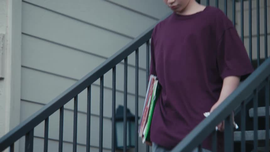Boy carrying books walks down an outdoor staircase