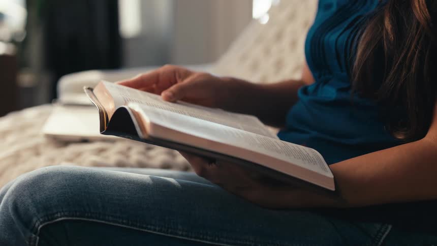 Woman sitting down picking up a bible and reading