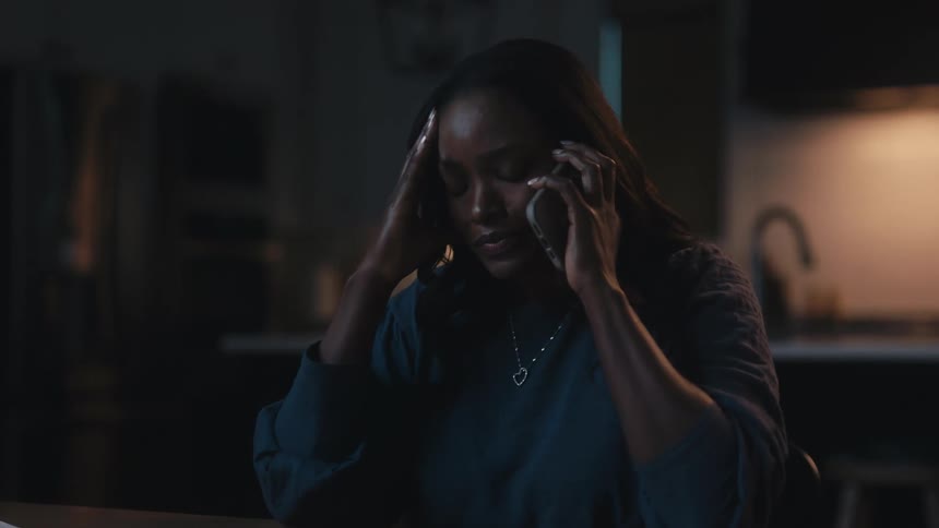 Woman sitting at table talking on phone and then hanging up with sad facial expression