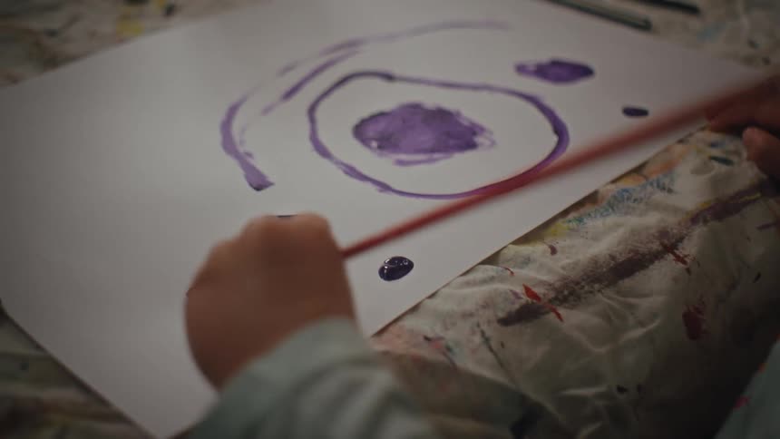 A clip of a little girl painting on a cardboard