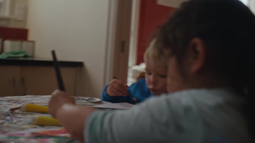 A boy and a girl sit at a table and paint with watercolors