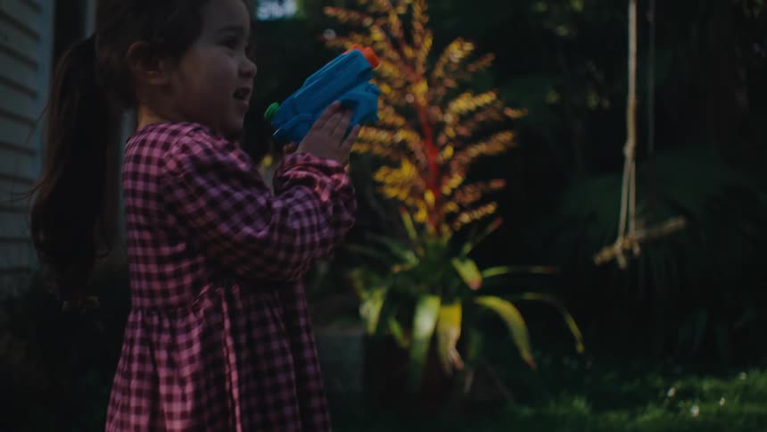 A little girl is in a backyard and she jumps up and then starts to take the conception out of the water happily