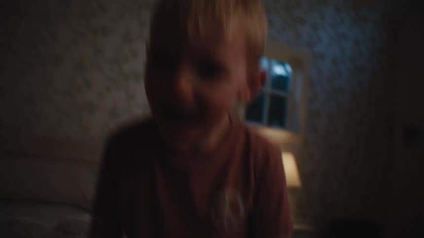 A young boy jumps on a bed