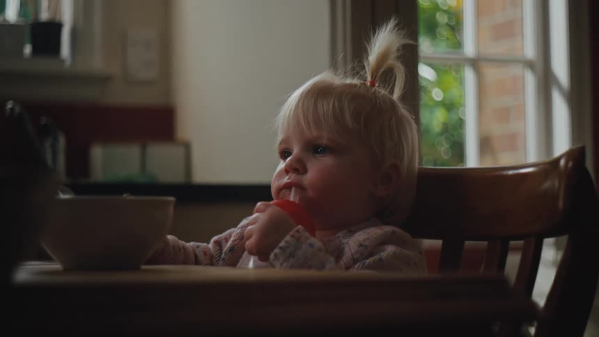 A child is drinking at the kitchen table
