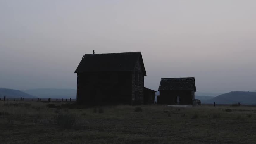 Small isolated houses in a field with mountains in the background