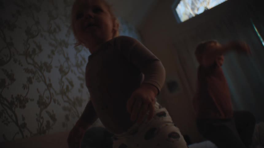 Two small children playing on the bed