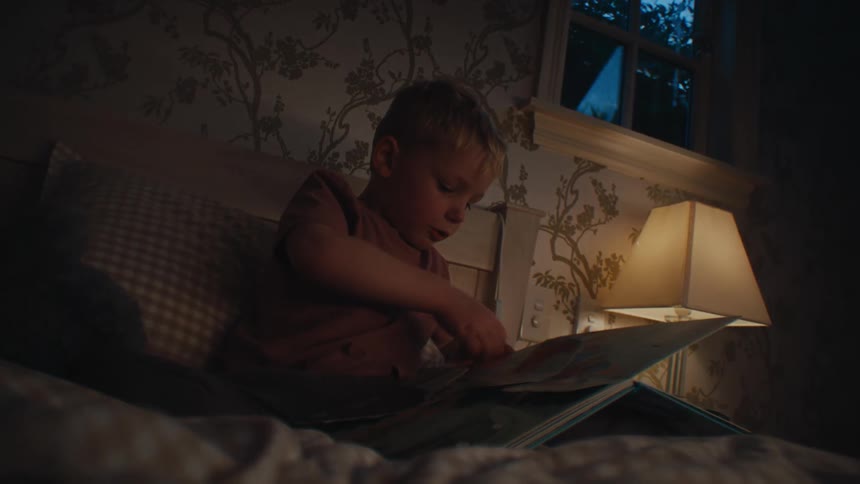 Boy sitting on bed and interacting with a book