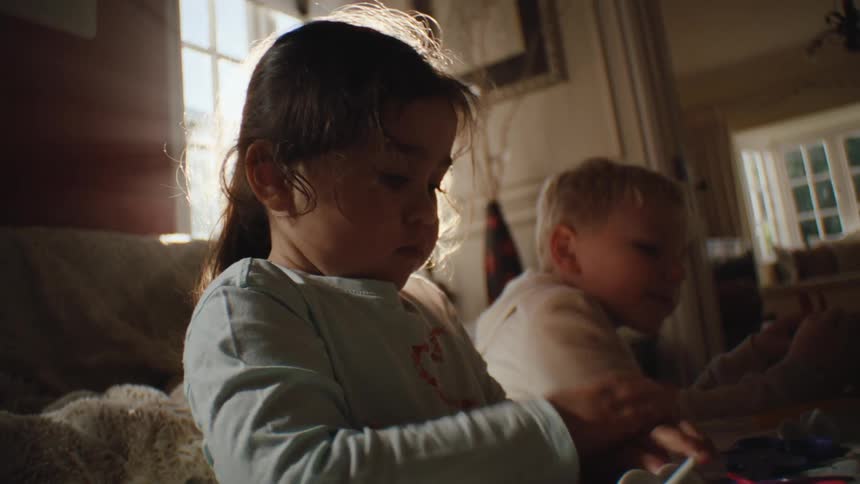 Two small children in the living room at a table playing