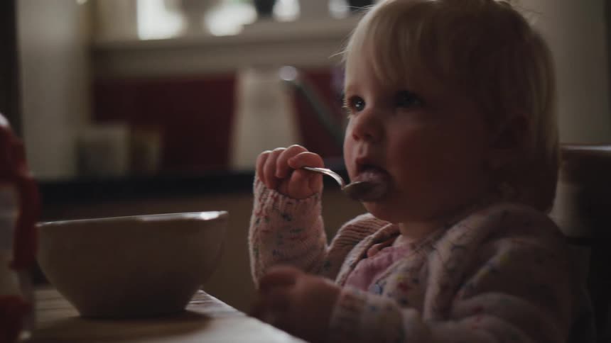 A young girl eats with a spoon