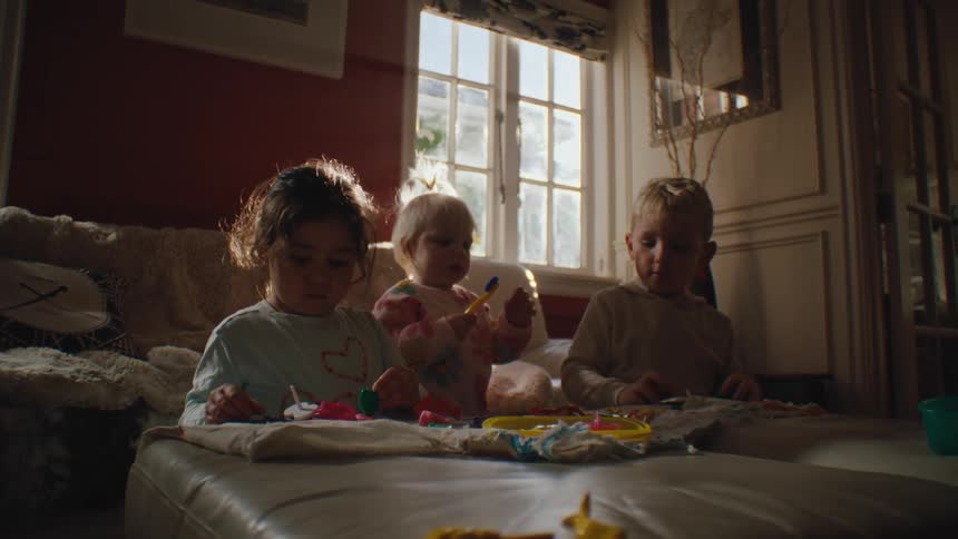 Three small children in the living room playing