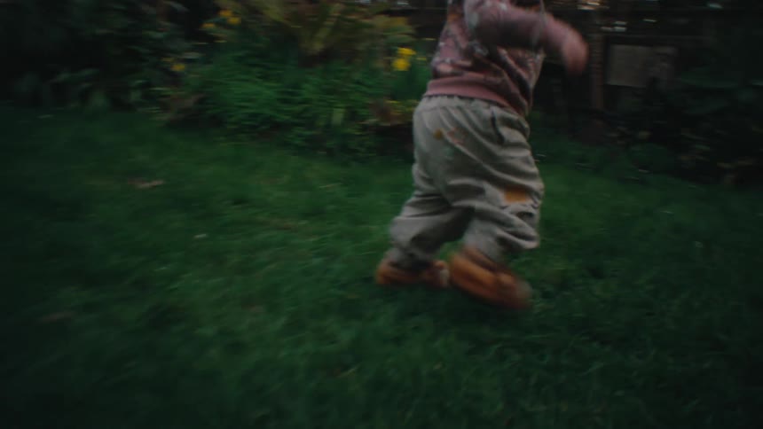 A child running on the green grass in the backyard