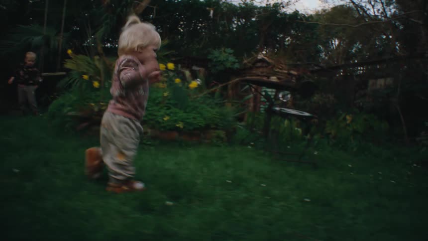 Small child walking in the yard with grass