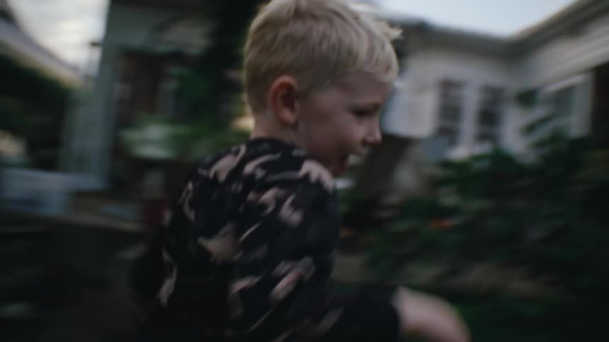 A child runs in the backyard near the house at morning