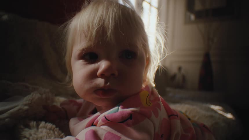 Little blonde child lying on the carpet in the living room