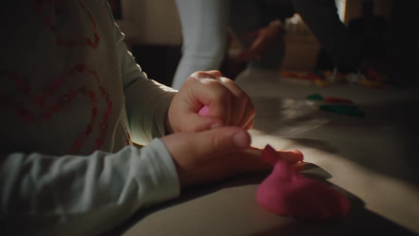 Mother cleans while her child plays with play doh