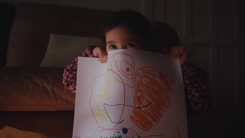 Little girl showing a white cardboard with a drawing
