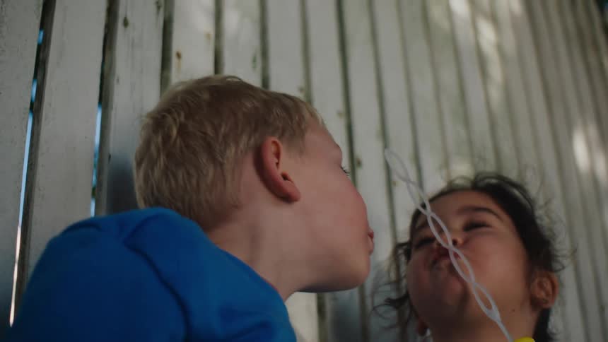 Two children bubbles from a wand