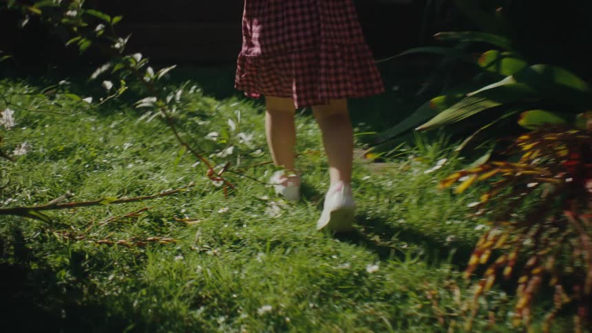 A young girl in a dress runs through a yard outside of a house