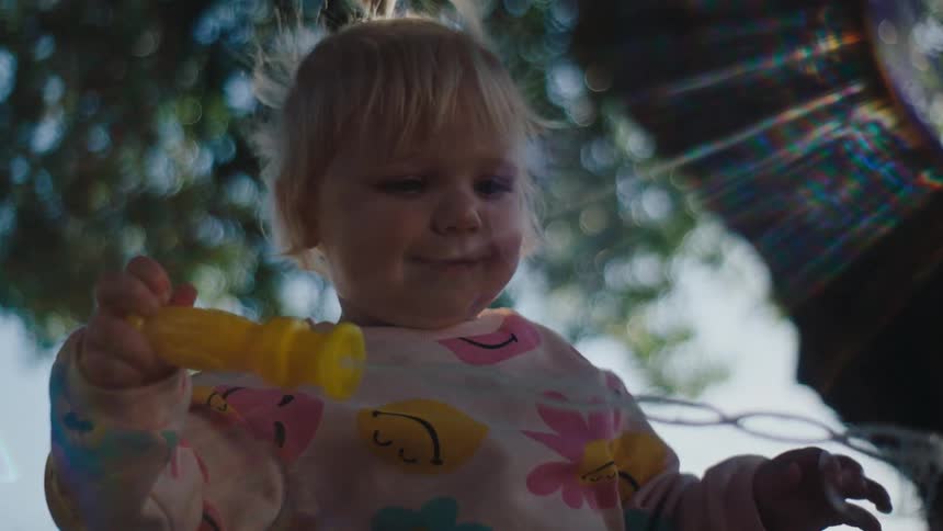 Closeup of a young child playing with a soap bubble toy while standing outdoors