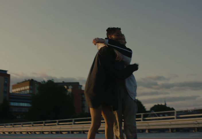 Two happy friends hug each other in the city streets at dusk