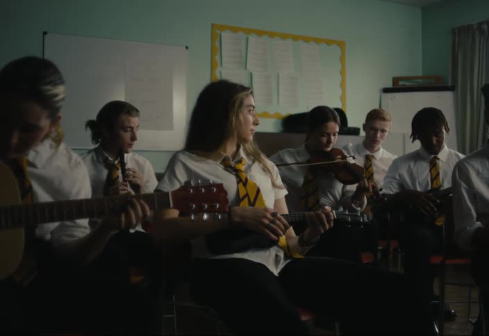 Group of teenagers sitting in a classroom playing different instruments