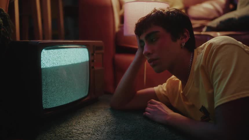 Teenager looking at a satellite tv with no signal inside his room