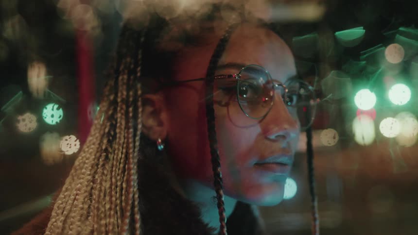 Portrait of a young woman with glasses sitting watching the city at night