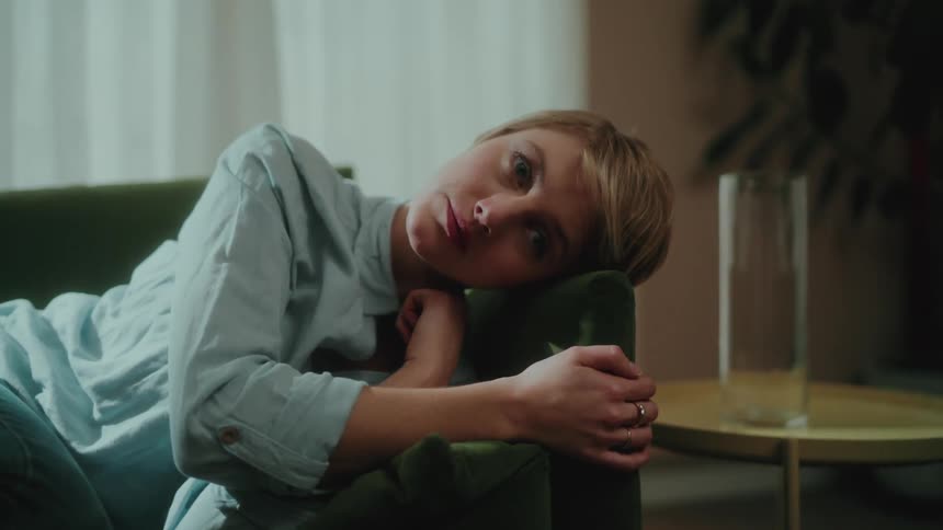 Woman lying in an armchair with a sad facial expression