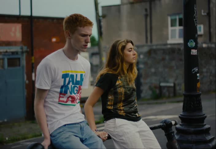 A young couple sitting next to each other on a bicycle stand in the city