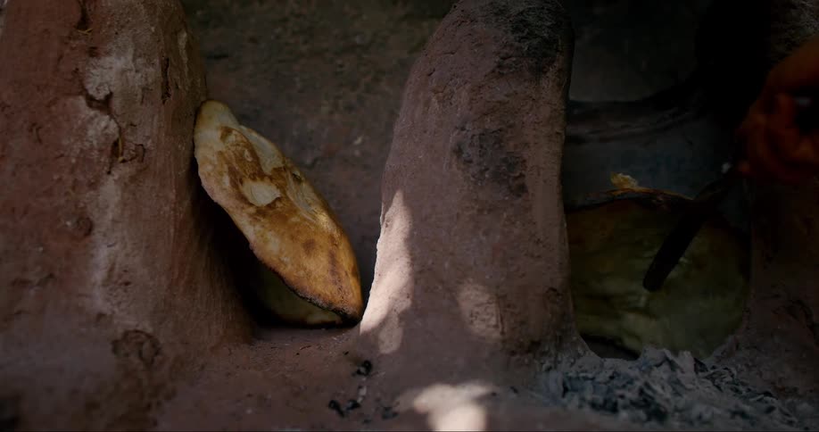 A person cutting and slicing pieces of a large brown material