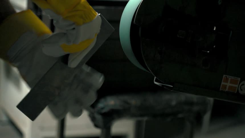 Hand with work gloves shaping metal on a machine