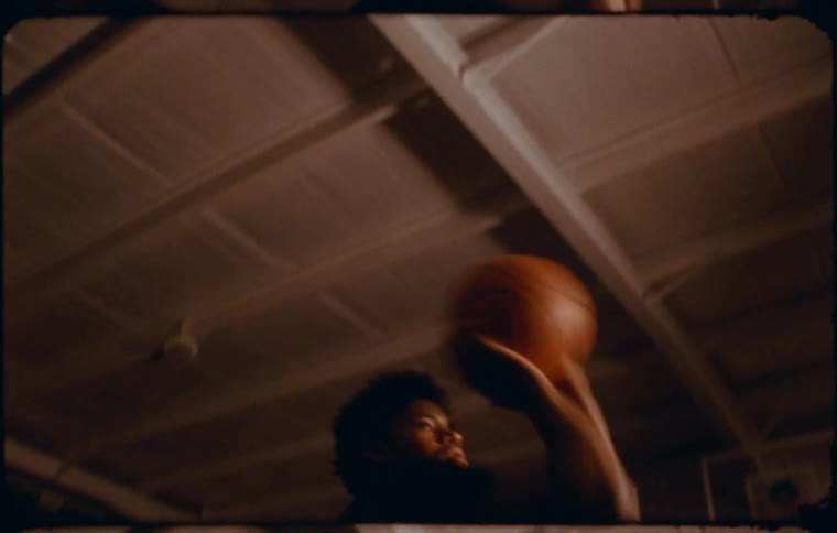 A young man shoots a basketball at the net on an indoor court