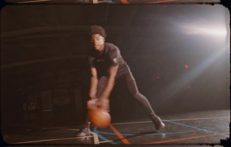 A young man is dribbling a basketball with focus and determination on an indoor court