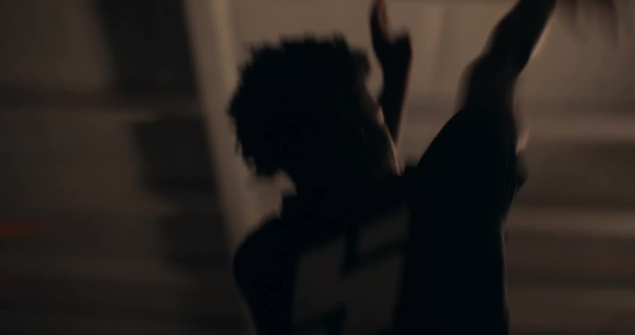 Youth throws the basketball while on a dimly lit interior basketball court