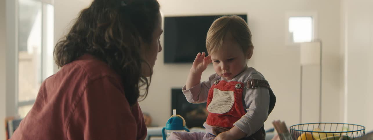 Mother talking to her little daughter who is sitting with her hands on her face