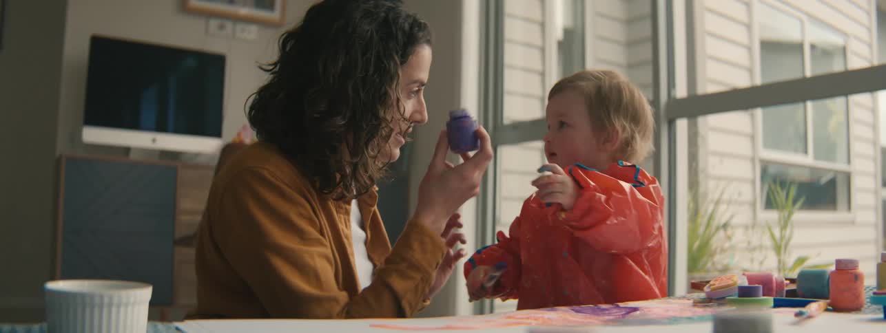 Mother and daughter sitting at a table playing with play dough and paint
