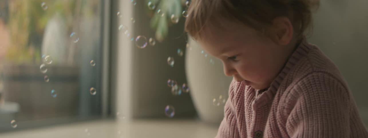 Little girl playing with a toy that releases soap bubbles