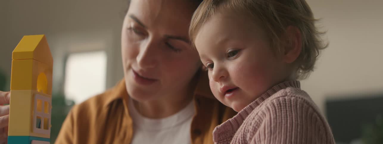 A woman and a young child are engaged in a playful building activity together