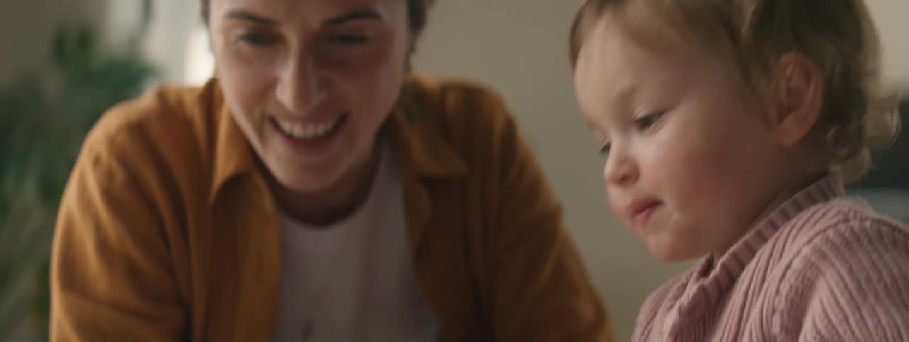 Mother and son reading a colorful illustrated book at home