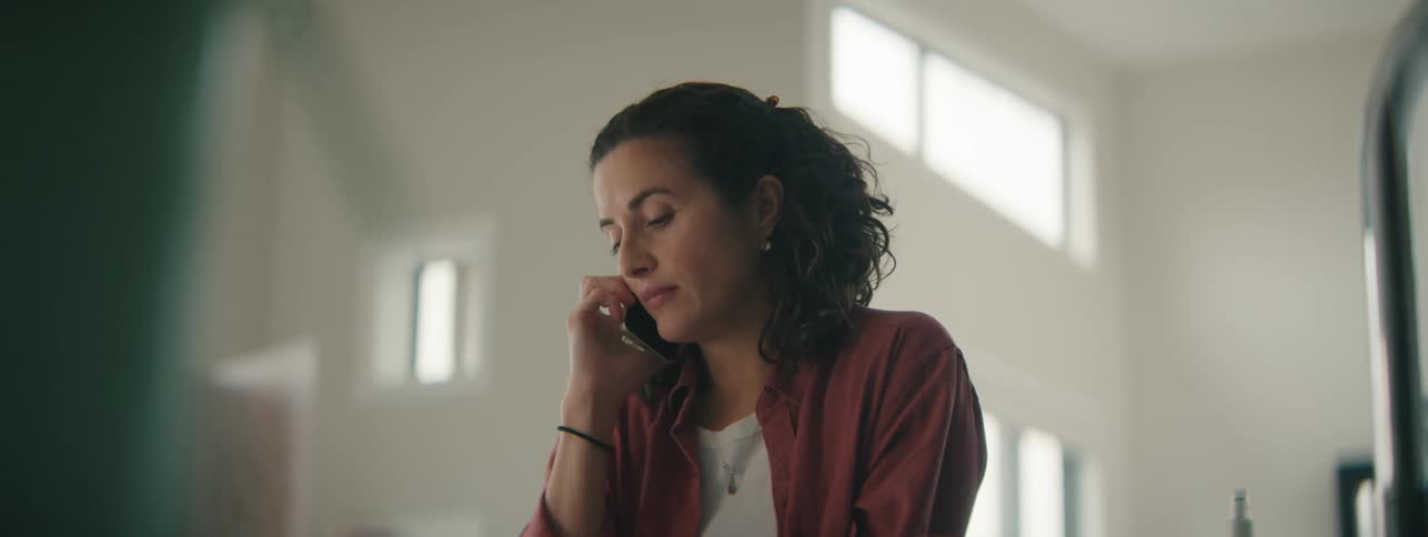 Overwhelmed young professional smiling during a quiet phone call.