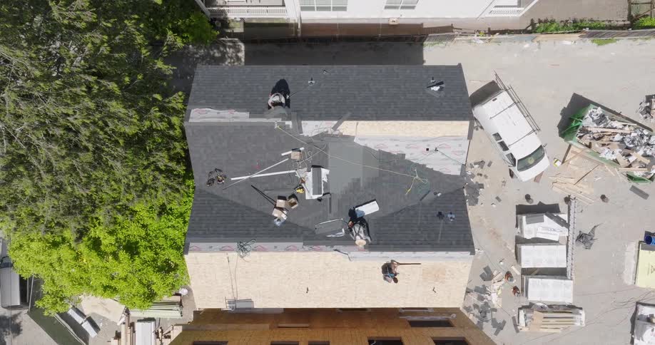 Slow descent over workers installing the roof on a new construction townhouse