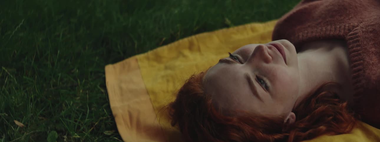 Young woman lying on a yellow towel on the grass