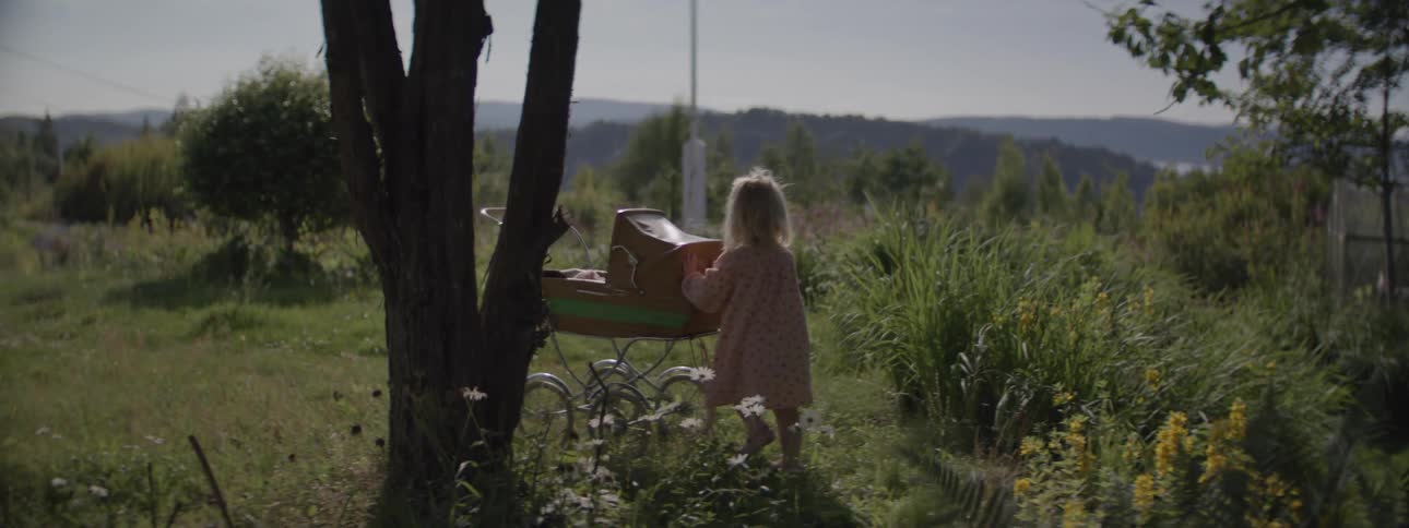 A toddler pushes a vintage baby stroller on a garden