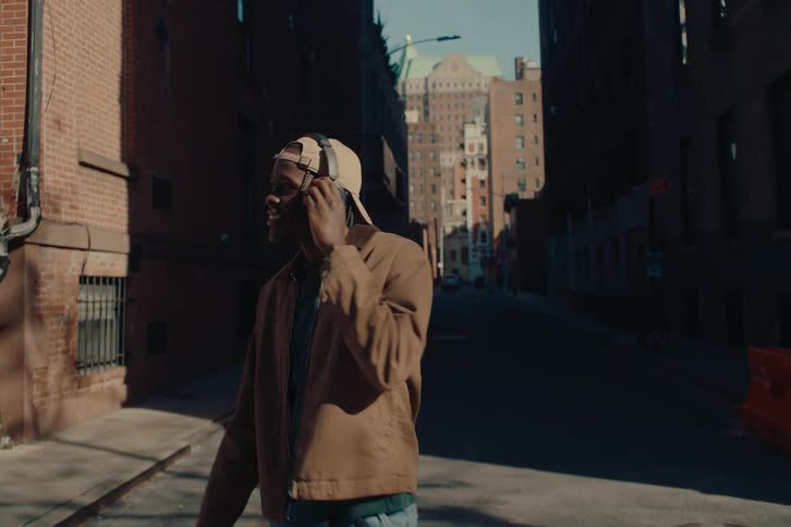 Man with happy facial expression walking across the street at the crosswalk while enjoying music on headphones