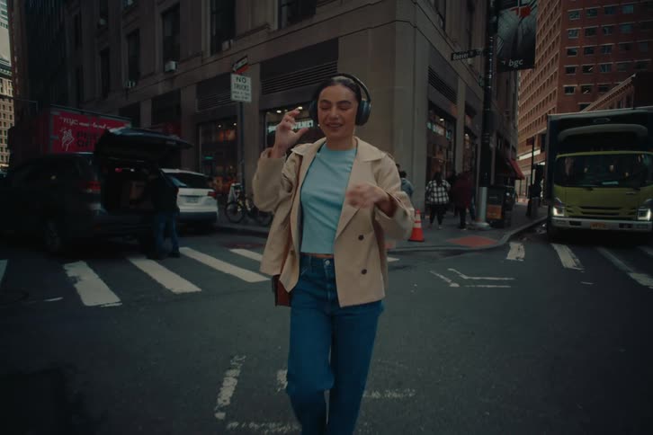 Woman crossing a street in the city with headphones and enjoying music