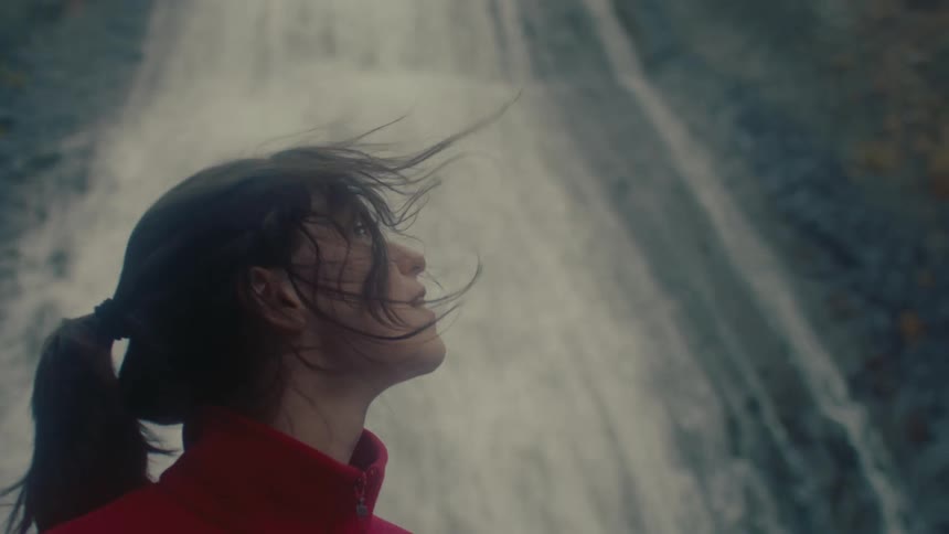 A woman is looking up at the waterfall