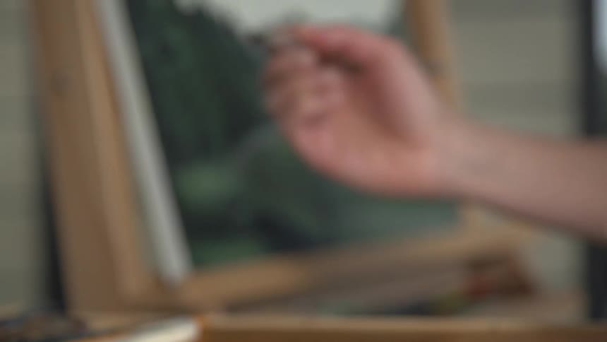 Person using a paint brush to gather paint before working on a portrait
