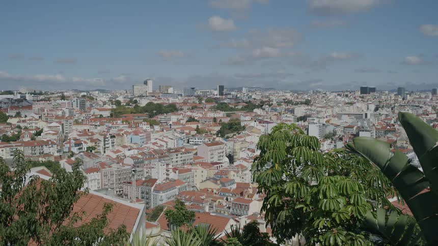 A panoramic view of a bustling city with colorful buildings nestled amidst rolling hills and under a clear blue sky