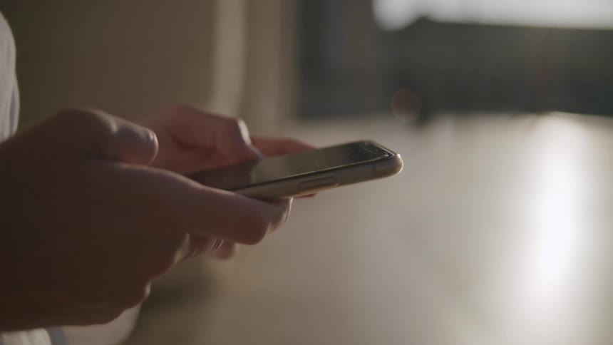 Hands of a woman typing on a smartphone