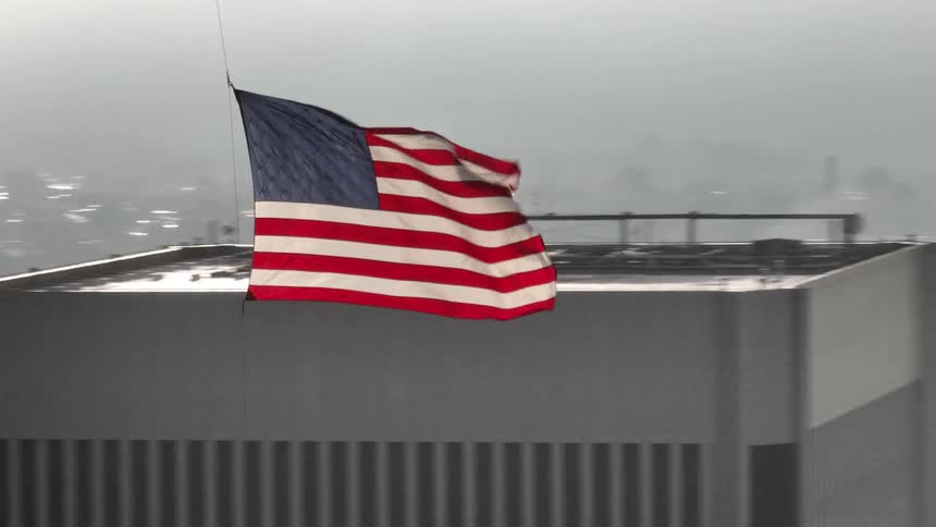 Aerial view of the us flag hanging overhead and a metropolis in the background